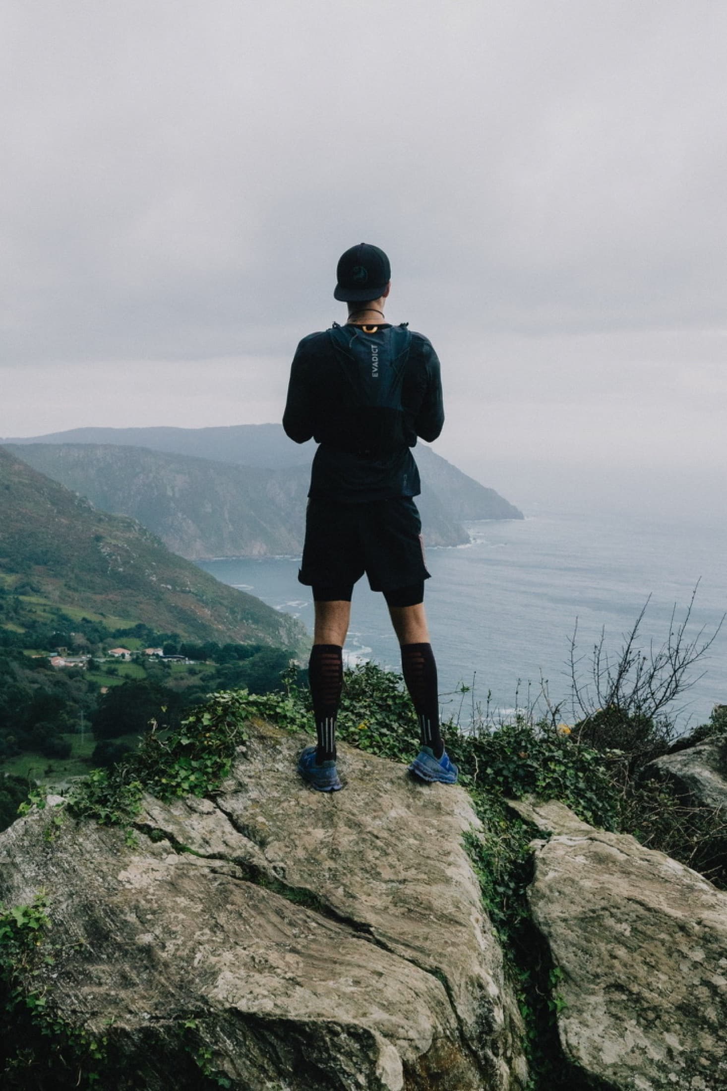 A runner on a coastal road with the Atlantic and a lighthouse headland behind.